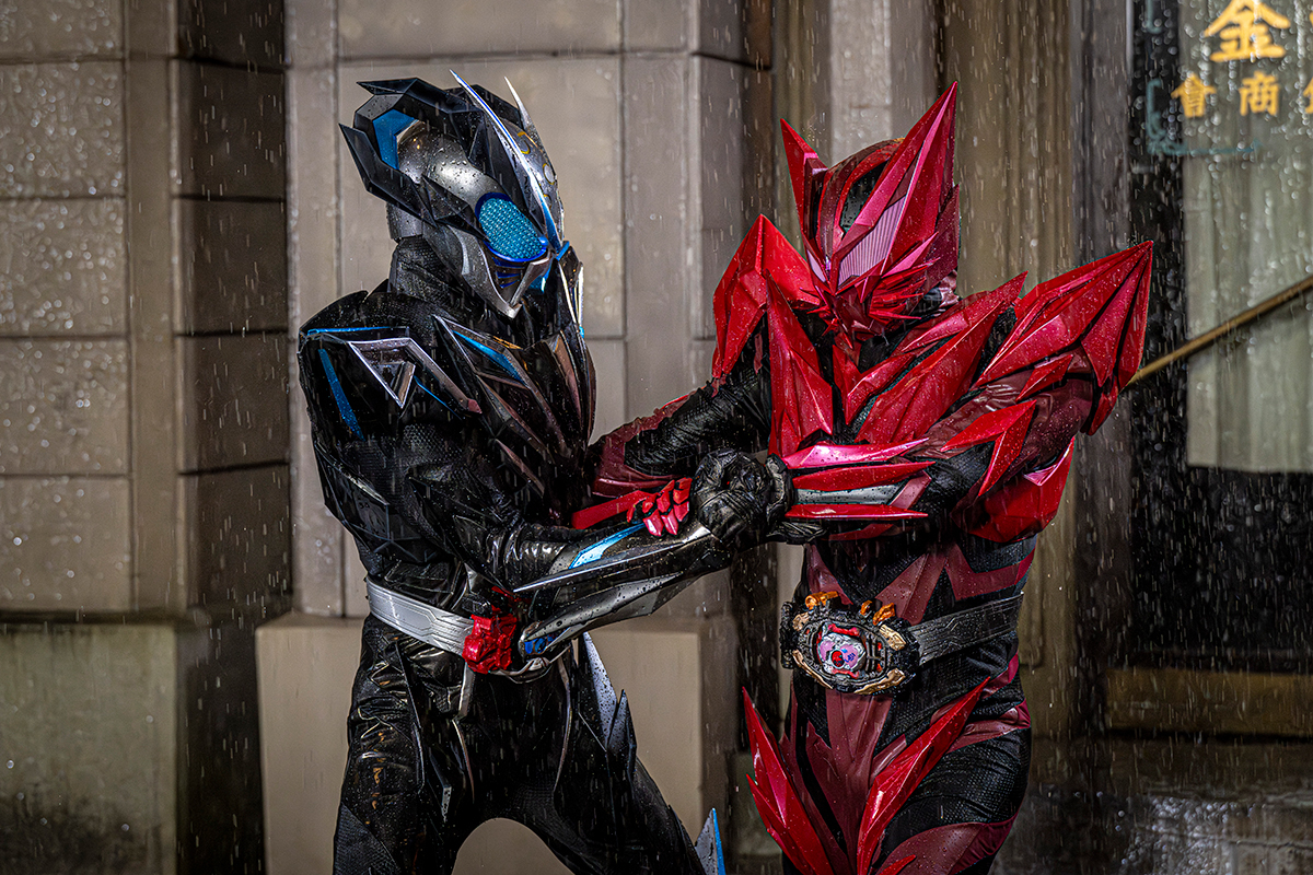 雨の中で腕をつかみ合う仮面ライダーマイスと赤い仮面ライダー